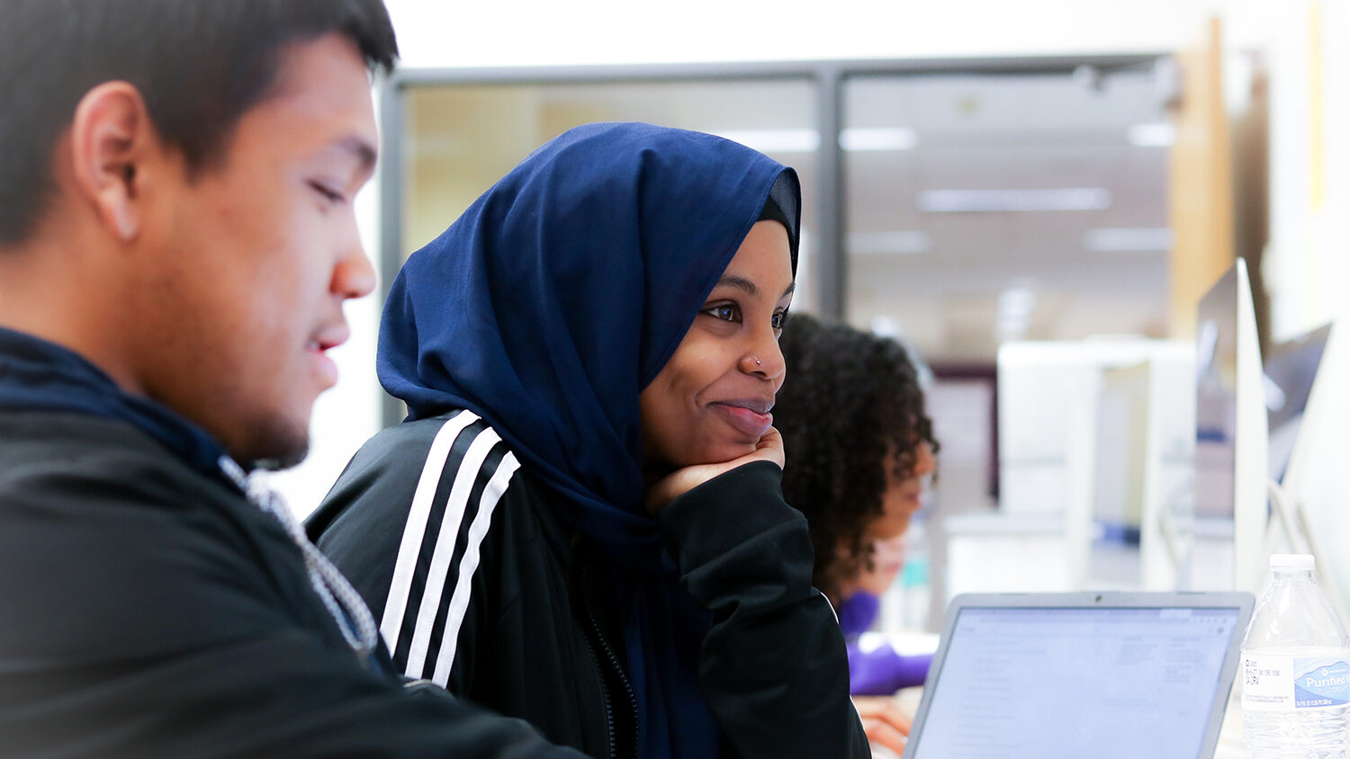 Three young adults look at computers