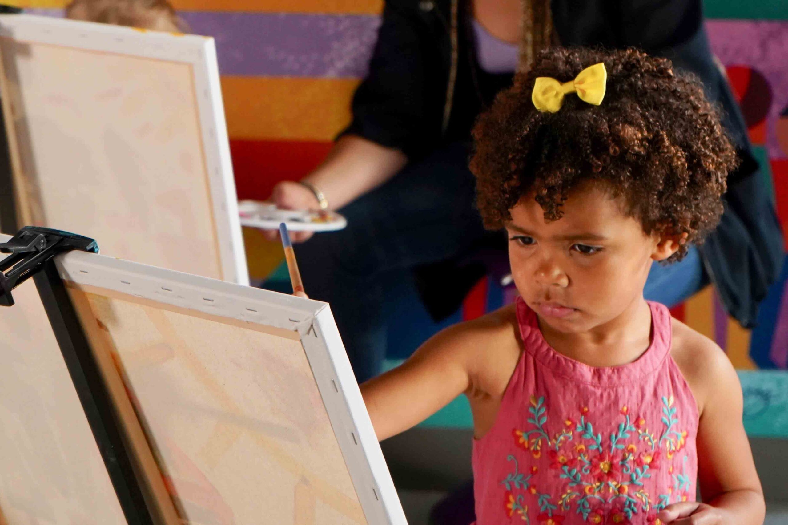 Child intently painting on a canvas