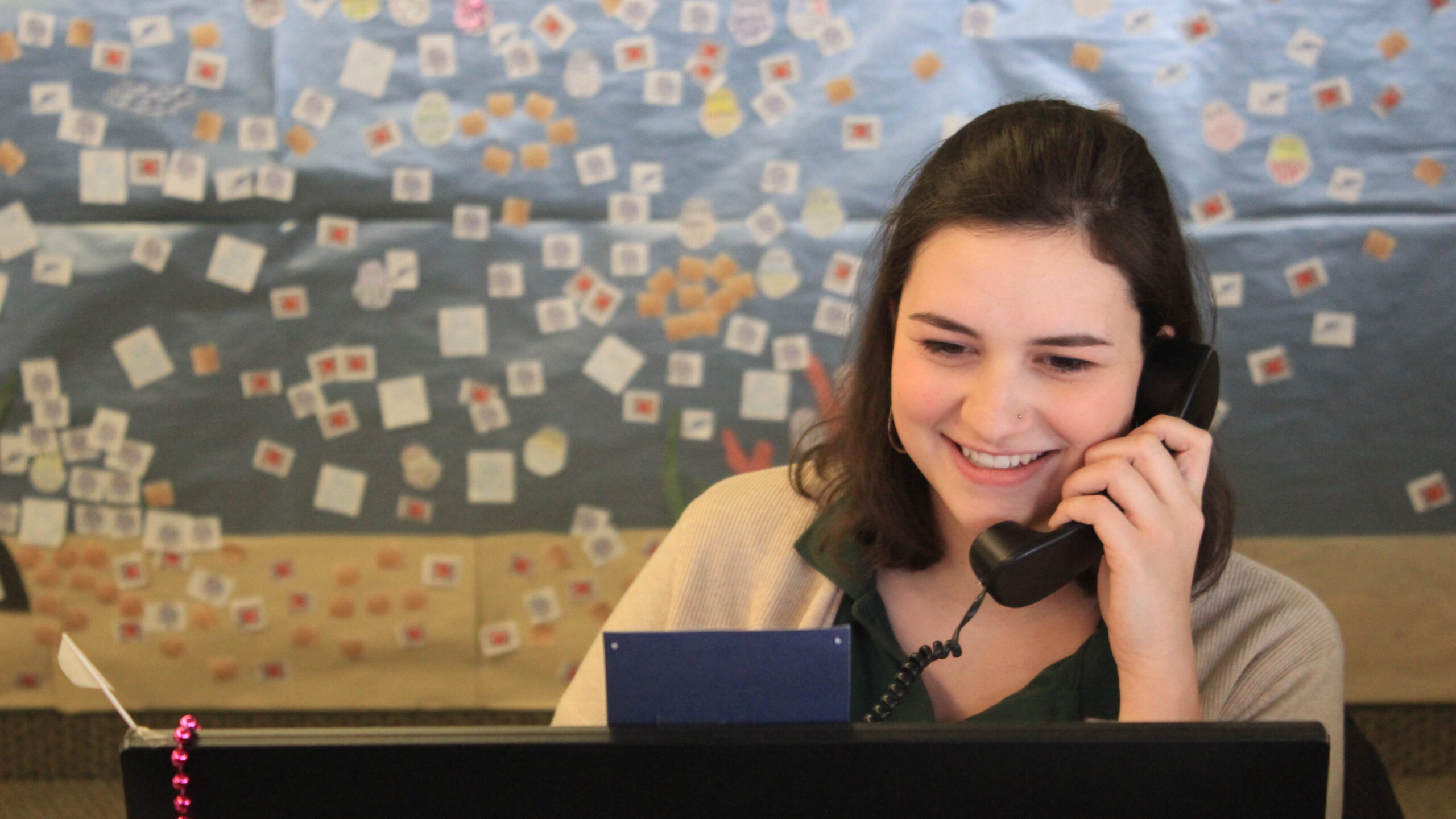 Smiling person on phone looking at computer