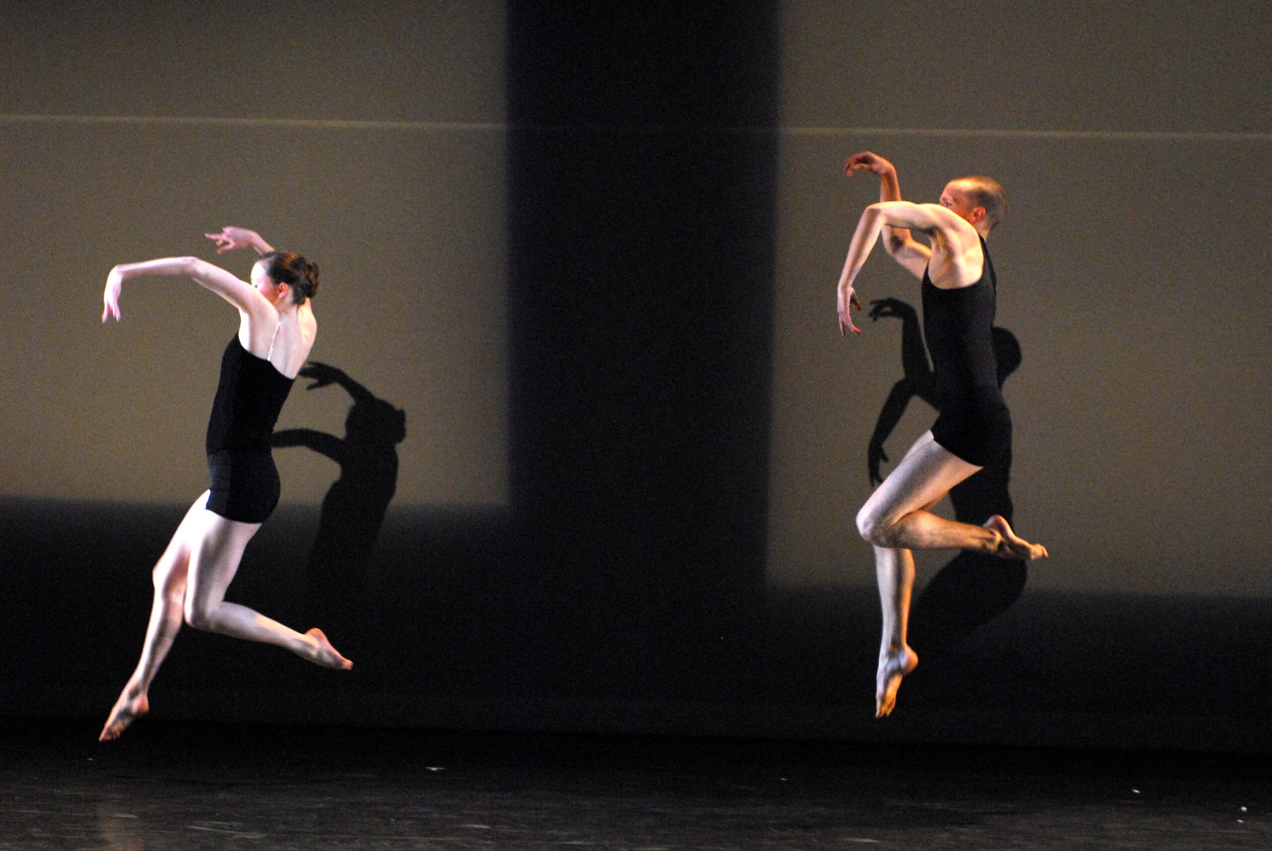 Two modern dance performers in motion on a stage