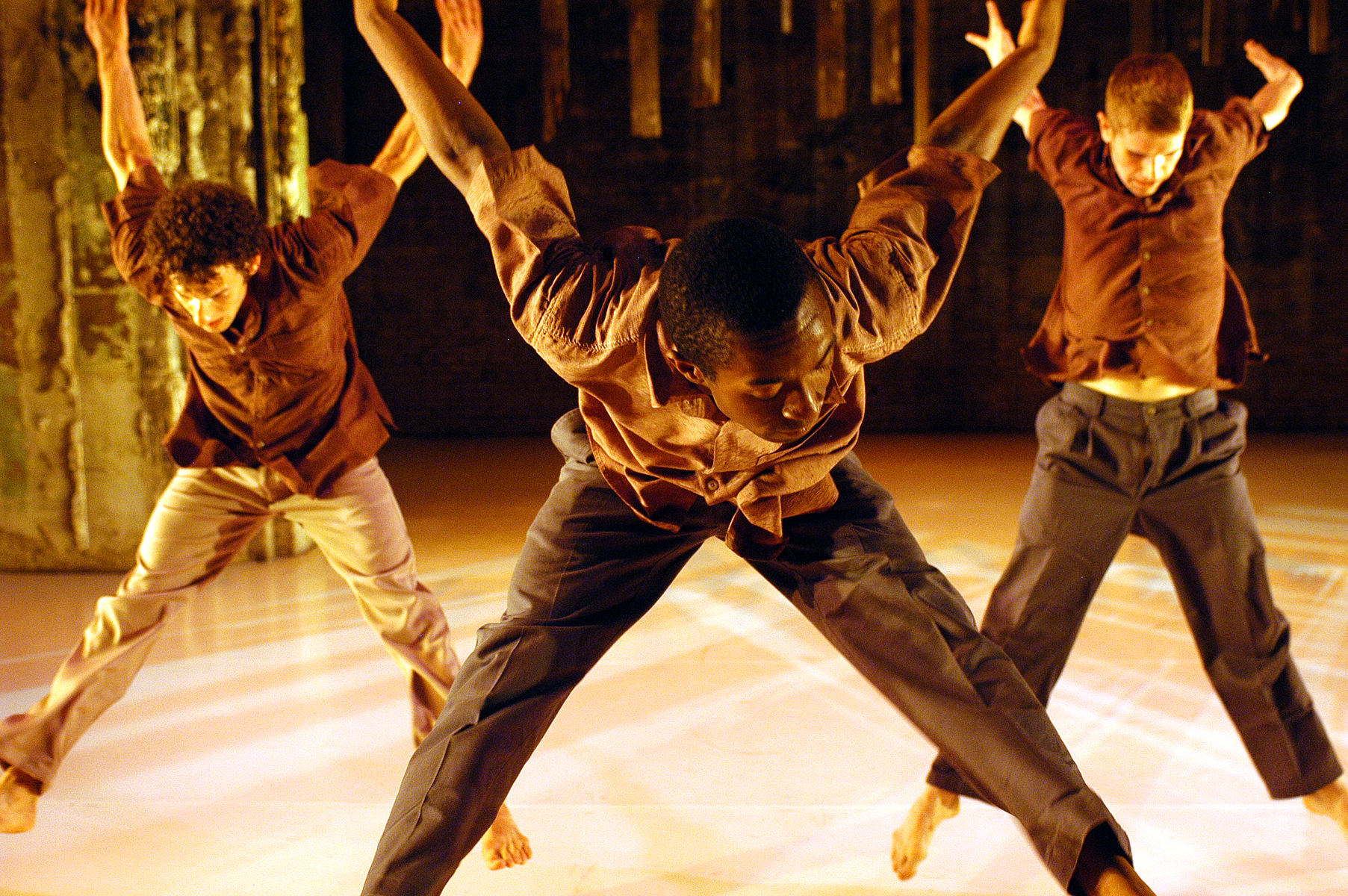 Three dancers jumping and raising arms in art cultural performance