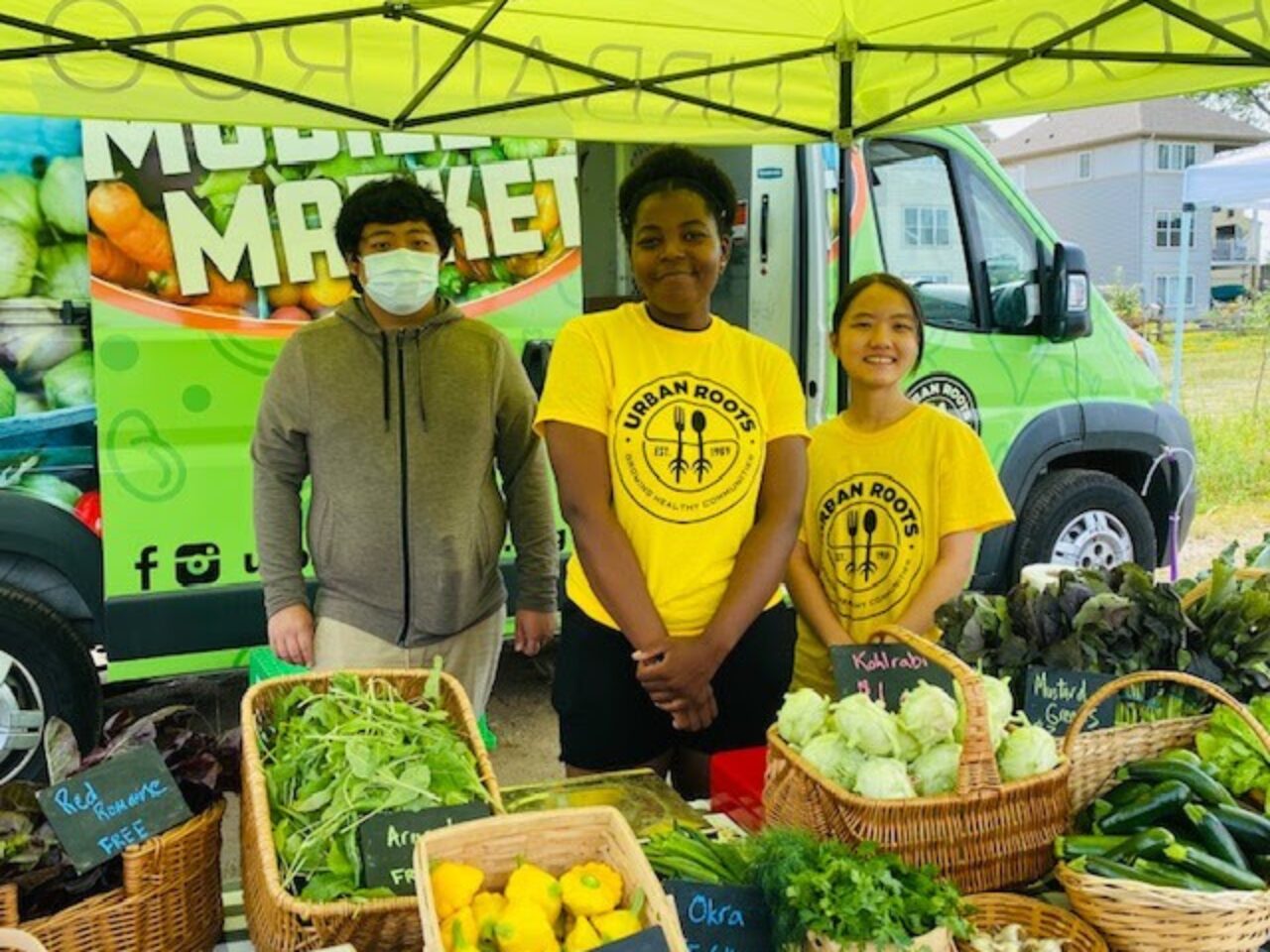 Three young people selling produce at farmerâ€™s market through Urban Rootsâ€™ Market Garden