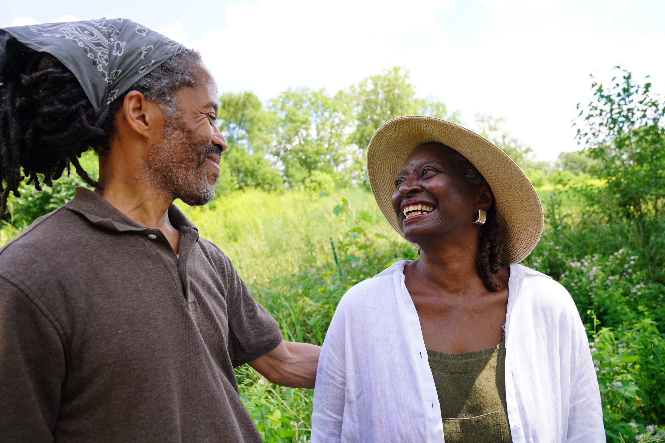 Frogtown Farm Board Member G.E. Patterson and Chair and Co-founder Soyini Guytonin in the lush outdoors smiling at each other
